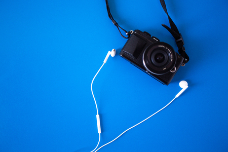 top view with digital camera and headphones White placed on a blue background,Holiday Adventure Travel Lifestyle Concep,Flat lay design creative space for journeyの写真素材