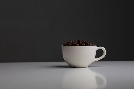 Coffee beans are placed in a white cup, placed on a white tabletopの写真素材