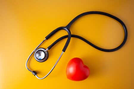 Stethoscope doctors and red heart cardiology placed on a Yellow table in the hospital,の写真素材