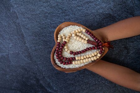 ZAKAT donation for Muslim according to religious principles during the Ramadan month, concept: rice grain in bow and rosary on black backgroundの写真素材