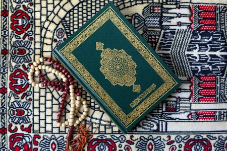 Quran and rosary laying on a wood background brown carpet in the mosque to read the prayer, In the month of Ramadan Muslim religion Islamic worshiping god faith and learn koranの写真素材
