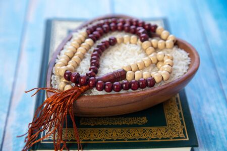 ZAKAT donation for Muslim according to religious principles during the Ramadan month, concept: rice grain in bow and rosary on woodの写真素材