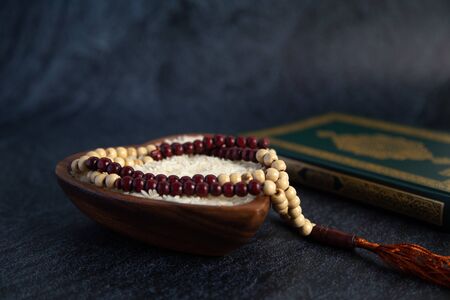 ZAKAT donation for Muslim according to religious principles during the Ramadan month, concept: rice grain in bow and rosary on black backgroundの写真素材