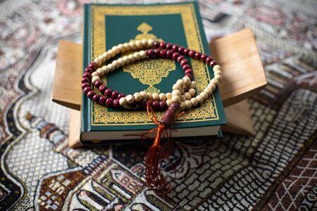 Quran and rosary laying on a wood background brown carpet in the mosque to read the prayer, In the month of Ramadan Muslim religion Islamic worshiping god faith and learn koranの写真素材