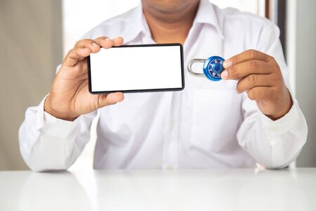 Asian man hand holding a smartphone and lock key, abstract  digital devices detox,Smartphone  unlock metal security lock key, Concept: hacker Password for data technology digital crime financeの写真素材