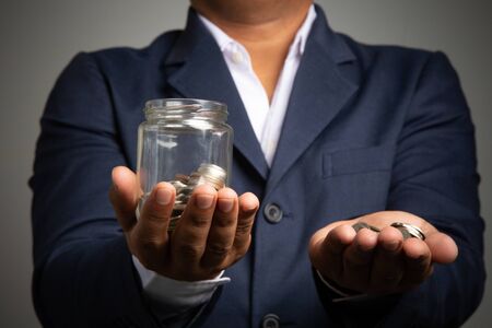 Businessman hand with putting money coins in the officeconcept: Saving money wealth and financial Personal, finance management  loan for a home,
 diagram chart earnings to plan profitの写真素材
