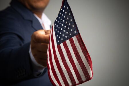 Businessman in a suit holding USA flag back background,
concept:4th of July independence day, symbol celebration for success education to  patriotic, country  democracy freedom to  Americanの写真素材