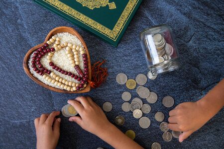 ZAKAT donation for Muslim according to religious principles during the Ramadan month, concept: rice grain in bow and rosary on black backgroundの写真素材