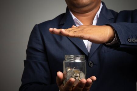 Businessman hand with putting money coins in the officeconcept: Saving money wealth and financial Personal, finance management  loan for a home,
 diagram chart earnings to plan profitの写真素材