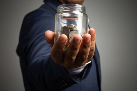 Businessman hand with putting money coins in the officeconcept: Saving money wealth and financial Personal, finance management  loan for a home,
 diagram chart earnings to plan profitの写真素材