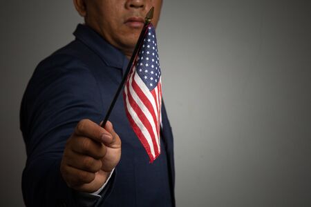 Businessman in a suit holding USA flag back background,
concept:4th of July independence day, symbol celebration for success education to  patriotic, country  democracy freedom to  Americanの写真素材