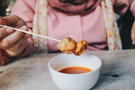 Women wearing pink veils eat Barbecue Meatballs Satay.の写真素材