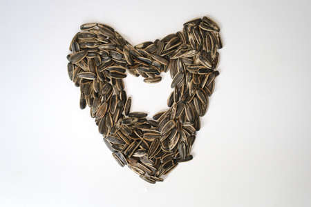 Pile of fried sunflower seeds with heart or love shape isolated on white background.の写真素材