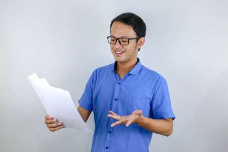Young Asian Man wear blue shirt is happy and smiling when pointing and look into the watch isolated...