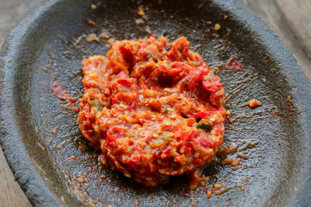 Fresh sambal served on stone mortar (cobek). Sambal is traditional sauce from indonesia made from chili.の写真素材