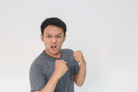 Angry and hate face of young Asian man in gray t-shirt with angry hand gesture