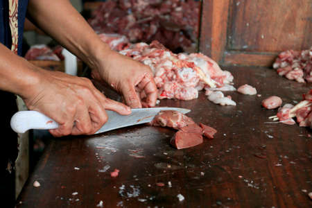 Butcher cutting raw lung or offal of cow and goat on a wooden chopping Board with knife.の写真素材