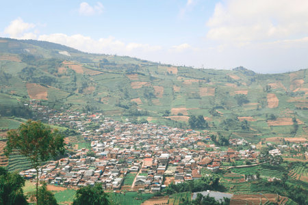 Aerial view of Dieng Plateau with town and hill in background.の写真素材