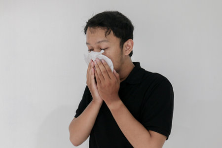 Sick asian man flu and cough is sitting with using tissue. Illness, influenza, pain concept. Healthcare and Concepts.の写真素材