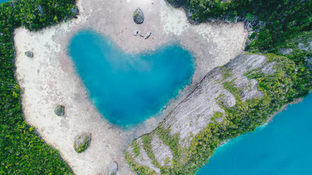 Aerial top view of Love Lagoon Karwapop with turquoise water in heart shape inside of rocky tropical island on Raja Ampat, Papua, Indonesia.の写真素材