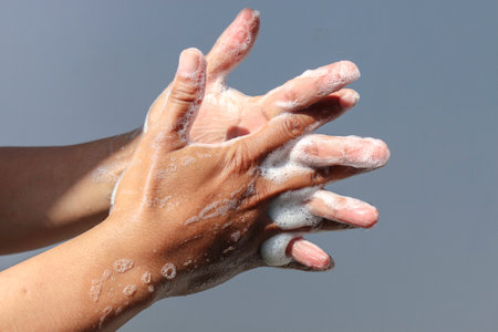 Man use soap and washing hands with grey background under the sunlight. Hygiene concept hand detail.の写真素材