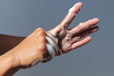 Man use soap and washing hands with grey background under the sunlight. Hygiene concept hand detail.