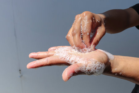 Man use soap and washing hands with grey background under the sunlight. Hygiene concept hand detail.の写真素材