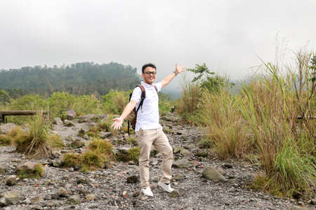 Young asian backpacker man is happy and enjoy traveling in mountain.