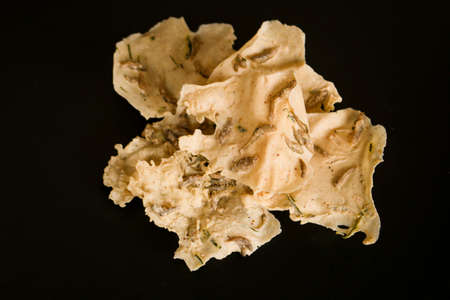 Rempeyek or fish crackers on wooden plate with salt fish or ikan teri isolated on white background. Fried savory Javanese crackers made from rice flour with salted fish by crispy flour mixture.の写真素材