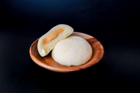 Bakpia Kukus Cake or Steamed Bakpia Cake with Cheese Flavour on wooden plate isolated on white background. Indonesia-china traditional cake from yogyakartaの写真素材