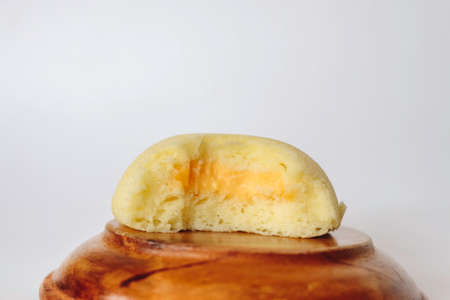 Bakpia Kukus Cake or Steamed Bakpia Cake with Cheese Flavour on wooden plate isolated on white background. Indonesia-china traditional cake from yogyakartaの写真素材