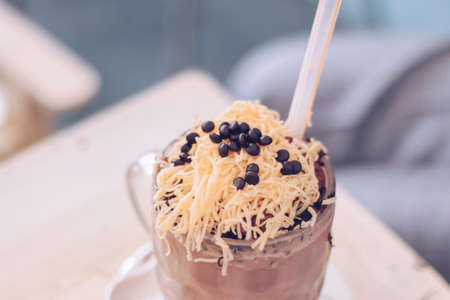 Chocolate Milkshake with chocolate cereals, cheese, and Choco chips in the big clear glass cup. Selective focus close-up on top of it and blurry background.の写真素材