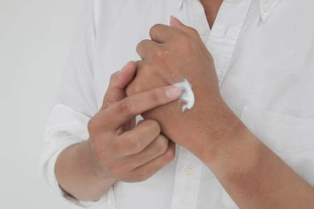 Asian handsome young man applying cream at his hand with smiley face, Skin care concept ,isolated on...