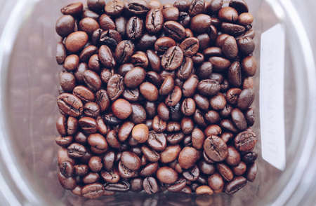 Fresh coffee beans in a plastic jar with brown colorの写真素材
