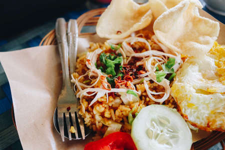A plate of oriental food Special fried rice from Indonesia with crackers isolated on wooden tableの写真素材
