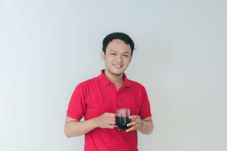 Young Asian man holding a cup of coffee standing over isolated white background happy with big...