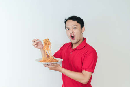 Portrait of Shock and Wow Young Asian man enjoy noodles. Eating lunch concept.の写真素材