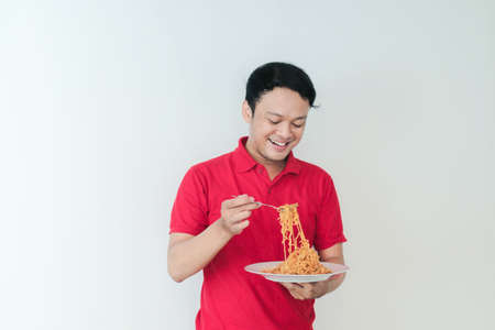 Portrait of happy Young Asian man enjoys noodles. Eating lunch concept.の写真素材
