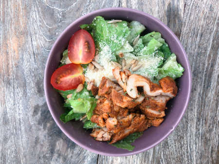 Green vegan salad from green leaves mix, vegetables, slices of chicken katsu. Top view on gray wood table.の写真素材