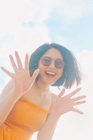 Portrait of happy smiling Asian woman with blue sky view from the bottom.の写真素材