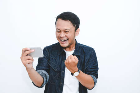 Smile and happy face of Young Asian man when playing game at phone in hand.の写真素材