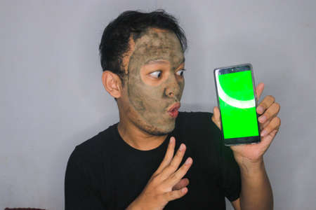 Shock Asian Man showing blank screen when he use beauty face mask