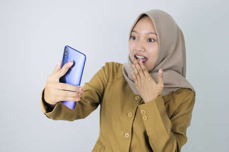 Shock government worker women when video call using a smartphone. PNS wearing khaki uniform.