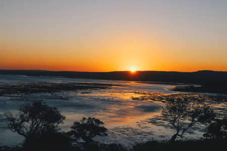 The sun shines with silhouette through the beach is receding and small hill at Rote Island,...
