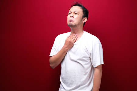 Sore throat of young asian man in red backgroundの写真素材