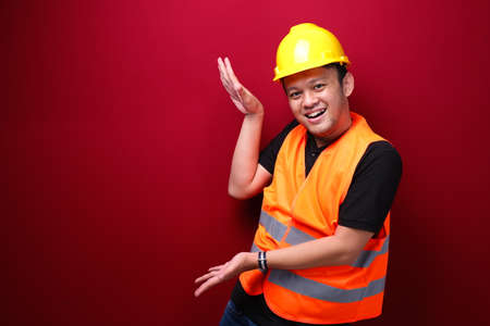 Smile and happy young asian man worker is with with hand point on empty spaceの写真素材