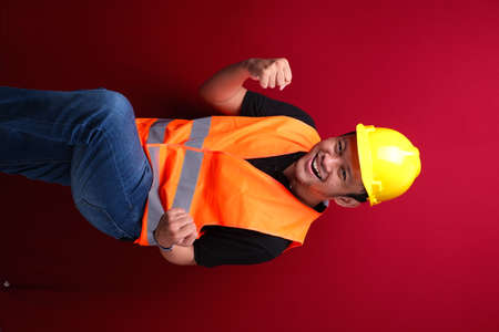 Happy excited and smiling young Asian man worker raising his arm up to celebrate success or achievement.の写真素材