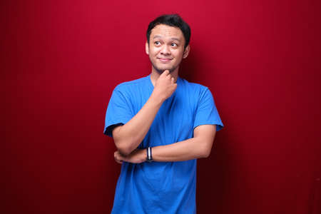 Thinking Young asian man is seriously think gesture on red backgroundの写真素材