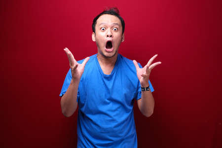 Wow and shocked face of Young Asian man with open hand gesture. Advertising model concept.の写真素材