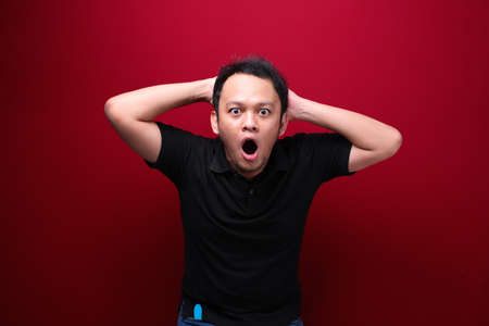 Wow and shocked face of Young Asian man with open hand gesture. Advertising model concept.の写真素材